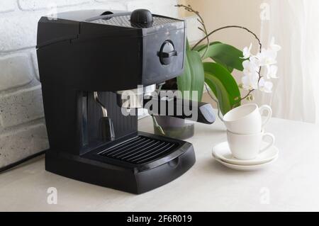 Eine schwarze Kaffeemaschine steht auf dem Küchentisch. Morgendliche Traditionen. Hausgemachtes Kaffeekonzept. Horizontale Ausrichtung. Stockfoto