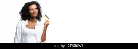 Nachdenkliche afroamerikanische Frau, die die Kreditkarte isoliert auf weißem Banner hält Stockfoto