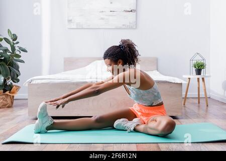 Lächelnde afroamerikanische Frau, die sich im Schlafzimmer aufwärmt Stockfoto