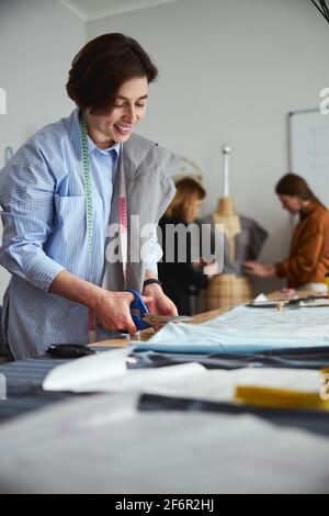 Dress Designer Schneiden Sie ein Stoffblatt mit einer Schere Stockfoto