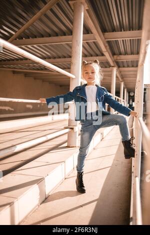 Stilvolle schöne Mädchen von etwa sieben in einer Denim-Jacke Spaziergänge auf der Straße Stockfoto