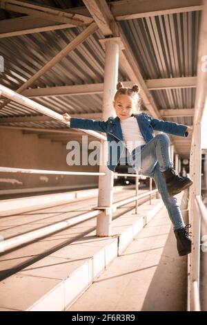 Stilvolle schöne Mädchen von etwa sieben in einer Denim-Jacke Spaziergänge auf der Straße Stockfoto