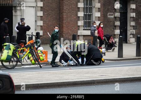 London, Großbritannien. 2.. April 2021. Die Polizei und der Londoner Krankenwagen-Service kümmern sich nach einer Kollision mit dem Straßenverkehr oder einem rtc um einen Fahrer, der gerade Essen geliefert hat. Stockfoto