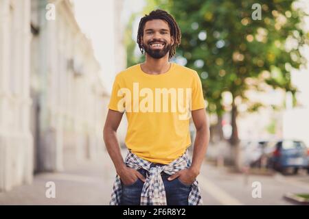 Foto-Porträt von jungen Mann trägt stilvolle Outfit Dreadlocks Frisur Lächelnd auf der Straße Stockfoto