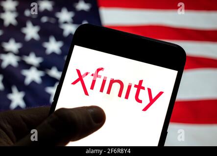 In dieser Abbildung sehen Sie das Logo des amerikanischen Internet-Fernsehdienstanbieters von Comcast, Xfinity, auf einem mobilen Android-Gerät mit der Flagge der Vereinigten Staaten von Amerika (USA), allgemein bekannt als die Vereinigten Staaten (USA oder USA), im Hintergrund. Stockfoto