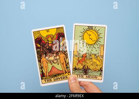 Hand mit zwei Tarot-Karten, dem Mond und den Liebenden. Stockfoto