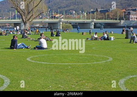 Heidelberg, Deutschland - April 2021: Weiße Kreise auf der Wiese am Neckarufer, um die Menschen während der Corona-Virus-Pandemie fernzuhalten Stockfoto