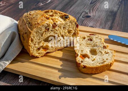 Hausgemachtes Vollkornbrot mit getrockneten Früchten und Nüssen, die auf einem Holzbrett geschnitten werden. Hochwertige Fotos Stockfoto