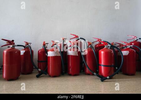 Ein Haufen abgelaufener Feuerlöscher auf dem Boden neben der Wand. Erneuerung der Feuerlöscher für Unternehmen. Stockfoto