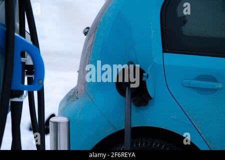 Ladegerät Stecker in Elektroauto auf verschneiten Winter Hintergrund eingesetzt. Grüne Energie. Stockfoto