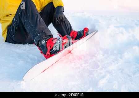 Snowboarder, der ein Snowboard auf dem Gipfel des Berges aufsetzt, bevor er frei bergab fährt. Stockfoto