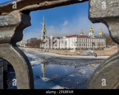 Russland, St.Petersburg, 02. April 2021: Der Glockenturm der St. Nikolaus-Marinekathedrale durch das geschmiedete Gitter an einem klaren, sonnigen Frühlingstag, einer Eisdrift Stockfoto
