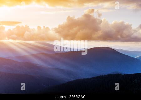 Morgensonne in Frühlingsbergen. Wunderschöne Sonnenstrahlen auf dem Hintergrund. Landschaftsfotografie Stockfoto