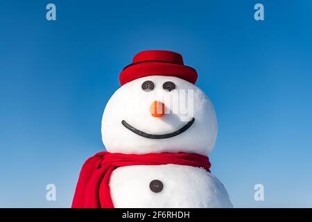 Lustiger Schneemann in stilvollem roten Hut und rotem Skalpenknopf Auf blauem Himmel Hintergrund Stockfoto