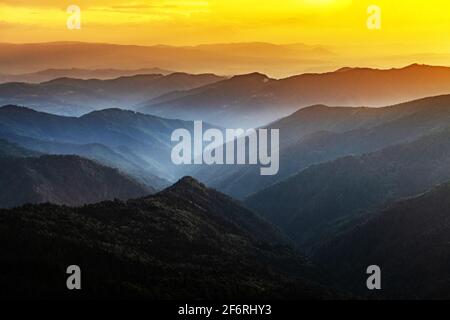 Morgennebel in den Frühlingsbergen. Schöner Sonnenaufgang im Hintergrund. Landschaftsfotografie Stockfoto