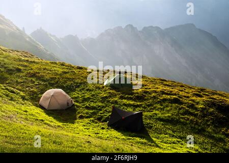 Drei Zelte Touristen zelten auf einer herrlichen Wiese in den Frühlingsbergen. Landschaftsfotografie, Reisekonzept Stockfoto