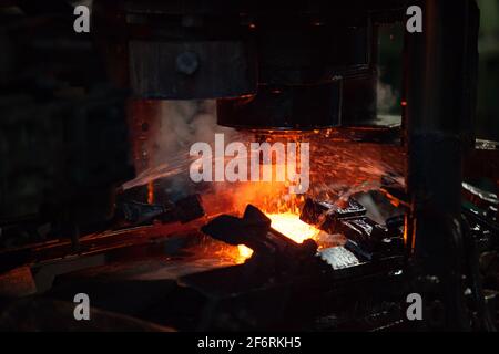 Lageranlage. Stanzen des Lagerrings auf der mechanischen Presse und Wasserkühlung des Metalls. Rot-heißes Metall. Nahaufnahme des Fotos. Stockfoto