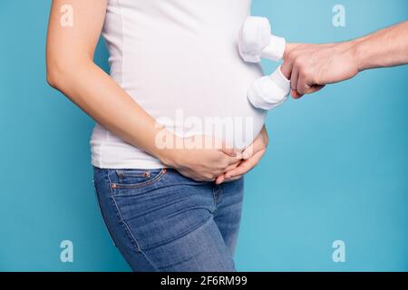 Foto Porträt von Bauch schwanger Frau trägt Jeans weiß t-Shirt mit mans Hand isoliert auf hellblauem Hintergrund Stockfoto