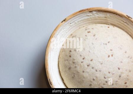 Teig mit natürlichem Sauerteig mit Leinsamen in einem Rattankorb. Das Konzept einer gesunden Ernährung. Der Stil des Lebens. Stockfoto