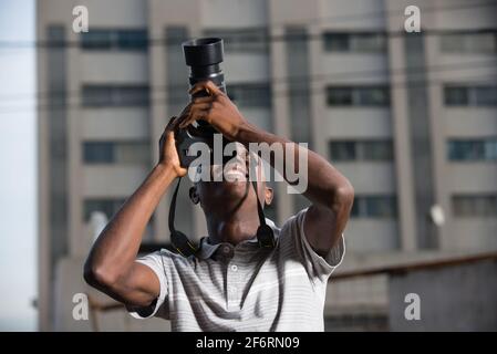 Junger Mann im Freien fotografiert dort oben lächelnd etwas. Stockfoto