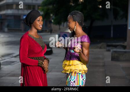 Junge Frauen stehen auf und sprechen lächelnd miteinander. Stockfoto