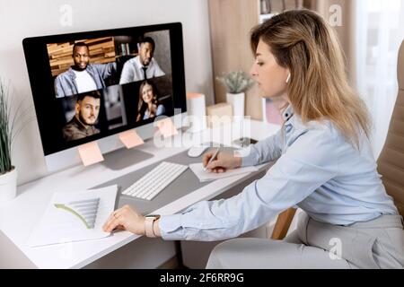 Serious elegante Geschäftsfrau hat Online-Konferenz mit Kollegen. Konzentrierte stilvolle Frau, die Finanzdiagramme lernt, mit diskutiert Stockfoto
