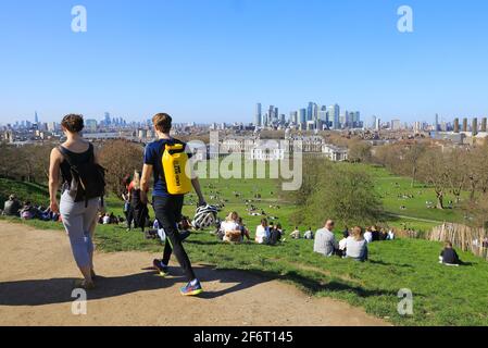 Die Menschen schauen sich den Blick über den Greenwich Park und in Richtung Canary Wharf an, in der frühen Frühlingssonne, SE London, Großbritannien