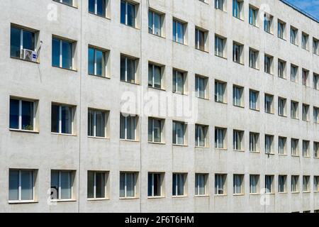 Modernes Bürogebäude, das den Rahmen mit langen Reihen quadratischer Fenster und einer weißen Fassade an der George Enescu st, Bukarest, Rumänien, füllt. Stockfoto