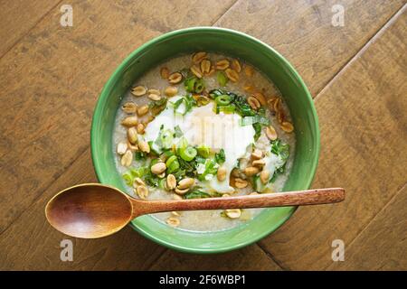 Schüssel mit Congee oder Reisbrei mit gebratenem Eiergrün Zwiebeln und Erdnüsse Stockfoto