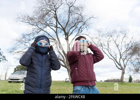 Chascomús, Buenos Aires, Argentinien: 2. Juli 2019: Zwei junge Männer, die mit einer Schutzbrille vorbereitet wurden, um eine totale Sonnenfinsternis in einem ländlichen Gebiet zu sehen. Stockfoto
