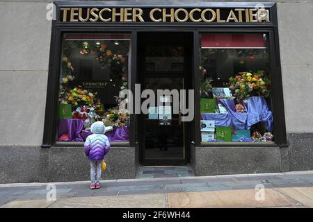 New York, USA. April 2021. Ein junges Mädchen blickt auf die Osterfeiertage-Ausstellung mit Pralinen im Teuscher Chocolatier-Geschäft im Rockefeller Center in New York, NY, 2. April 2021. (Foto von Anthony Behar/Sipa USA) Quelle: SIPA USA/Alamy Live News Stockfoto