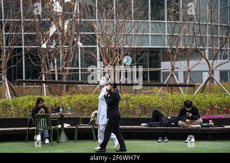 Seoul, Südkorea. 02. April 2021. Frauen mit Gesichtsbesamung laufen an jungen Menschen vorbei, die in der I Park Mall in Seoul sitzen und sich entspannen. Kredit: SOPA Images Limited/Alamy Live Nachrichten Stockfoto