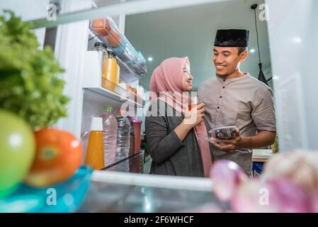 Schönes Paar muslim brechen die schnelle iftar vor Der offene Kühlschrank Stockfoto
