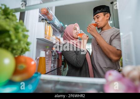 Schönes Paar muslim brechen die schnelle iftar vor Der offene Kühlschrank Stockfoto