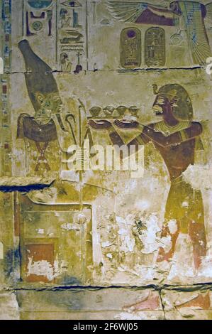 altägyptische Hieroglyphen gemalte Schnitzerei, die den Pharoah Seti zeigt, der ein Opfer an den gott der Regeneration Osiris macht. Tempel von Oiris, Abydos, Stockfoto