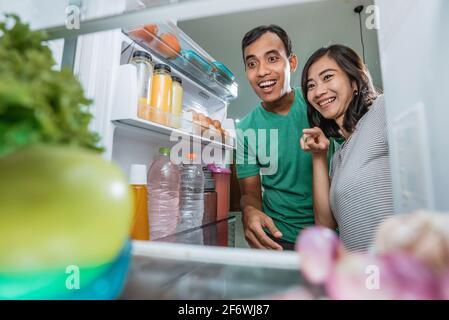 Aufgeregt Paar öffnen Sie den Kühlschrank in der Küche Vorbereitung Zusammen kochen Stockfoto