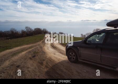 Eine Schotterstraße, die zum Horizont führt. Spektakulärer Blick auf das Meer und den blauen Himmel am Abend. Offroad 4x4 Auto Stockfoto