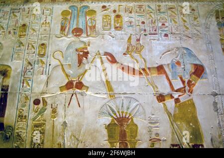 altägyptisch bemalte Hieroglyphen-Schnitzerei, die den gott der Unterwelt zeigt - Osiris mit dem Ibis-Kopf-gott Thoth, der mit Weisheit assoziiert ist Stockfoto