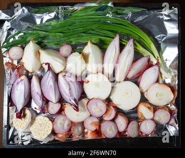 Zwiebeln und Knoblauch auf einer Pfanne, die im Ofen geröstet werden kann. Draufsicht. Stockfoto