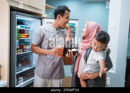 muslimische Familie, die im Stehen iftar das Fasten bricht Die Küche Essen Datteln Obst Stockfoto