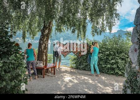 Touristen, die an Hunderten von Vorhängeschlössern auf einem herzförmigen Zaun im Naturschutzgebiet Orter Bucht in der Nähe des Traunsees fotografieren Stockfoto
