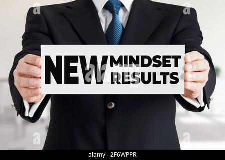 Geschäftsmann zeigt ein Banner mit der Botschaft New Mindset neue Ergebnisse. Änderung der Denkweise und Selbstentwicklung im Geschäftskonzept. Stockfoto