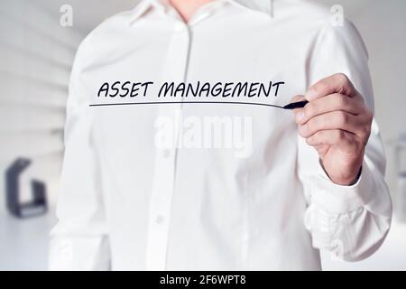 Businessman Hand hält einen Stift und unterstreicht die Worte Asset Management auf dem virtuellen Bildschirm. Konzept zur Verwaltung von Geschäftsressourcen. Stockfoto