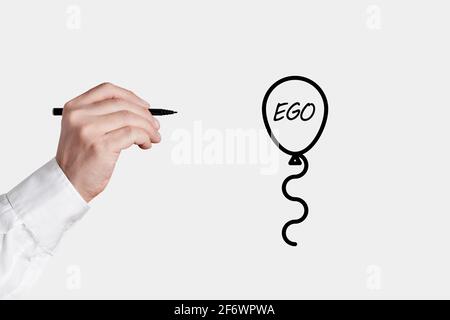 Geschäftsmann mit einem Stift ist dabei, eine Ballon-Ikone mit dem Wort Ego zu poppen. Senken oder befreien Sie Ihr Ego-Konzept. Stockfoto