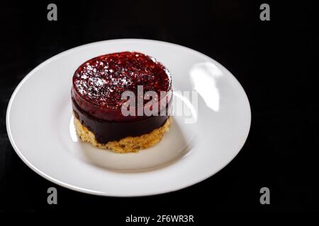 Biskuitkuchen auf einem Teller mit Himbeer-Gelee auf der Oberseite bedeckt. Süßes Dessert. Stockfoto