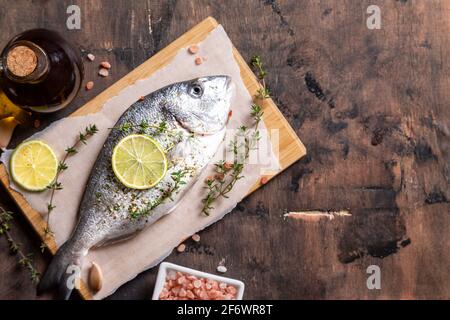 Frischer roher dorado-Fisch. dorado-Fisch und Zutaten zum Kochen - Limette, Salz, Öl, Knoblauch, Thymian und Kräuter Stockfoto