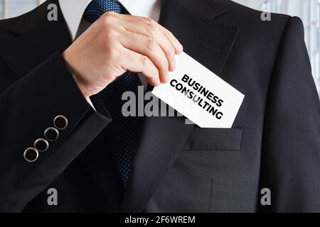 Geschäftsmann nimmt eine Visitenkarte mit dem Wort Unternehmensberatung. Konzept des Unternehmensberaters. Stockfoto