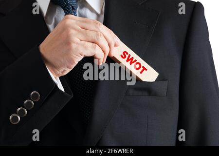 Geschäftsmann nimmt einen Holzblock mit dem Wort SWOT aus seiner Tasche. Business Marketing swot Analyse Konzept. Stockfoto