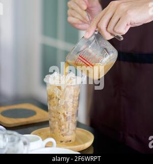 Kaffee von Hand aus einer Messbecher in eine Plastikschale gießen (Closeup ). Professioneller Barista, der Kaffee auf der Theke zubereitet. Stockfoto