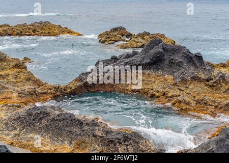 Natürliches vulkanisches Gestein in der Nähe von Ponta da Ferraria, dem Ort, an dem sich heiße Quellen mit Meerwasser vermischen, auf der Insel Sao Miguel, Azoren, Portugal Stockfoto